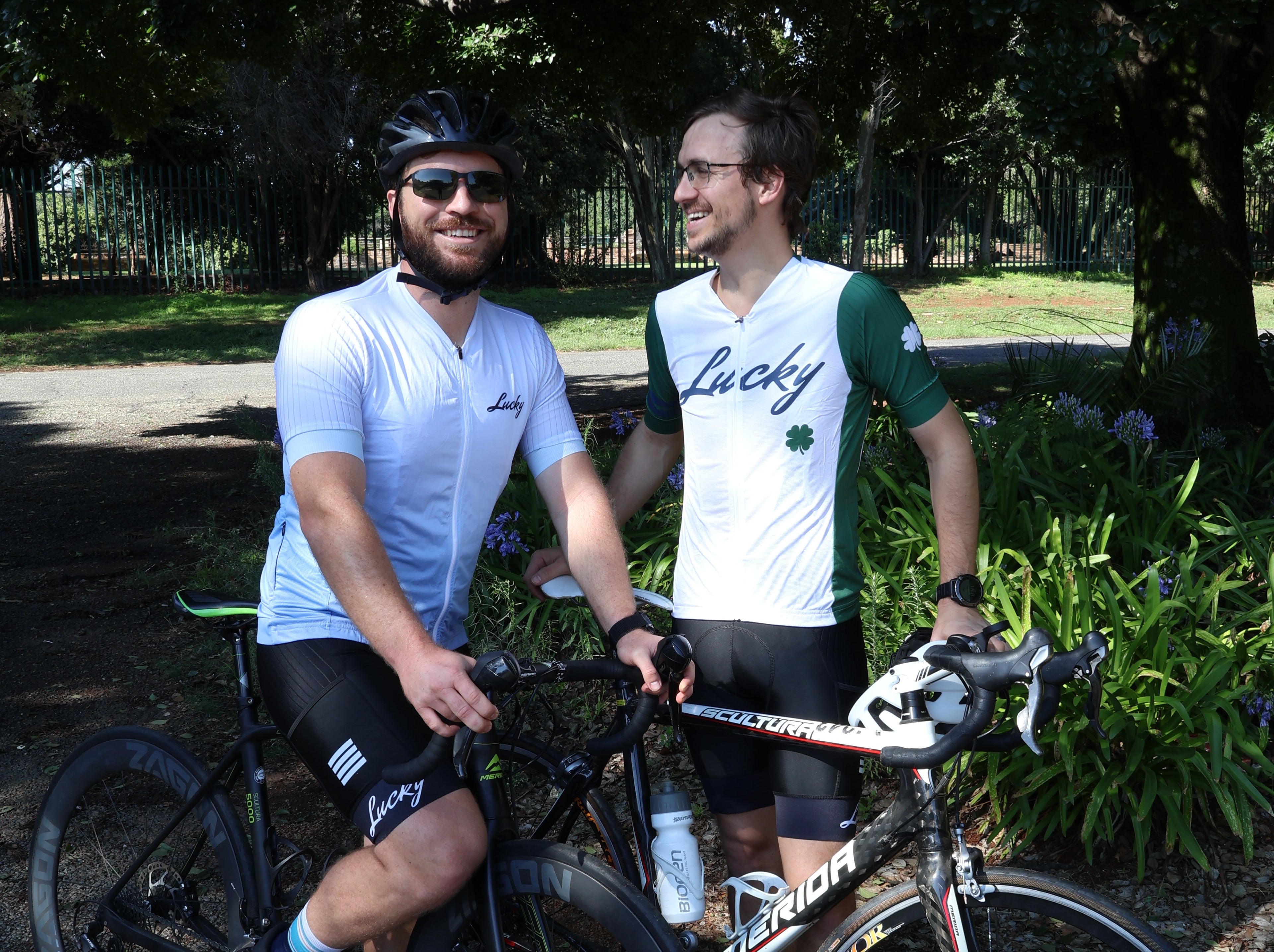Two cyclists with their bicycles on a path surrounded by greenery
